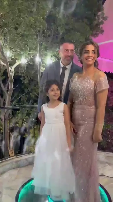 A family posing together on the lit 360 cam platform as the camera arm swings past