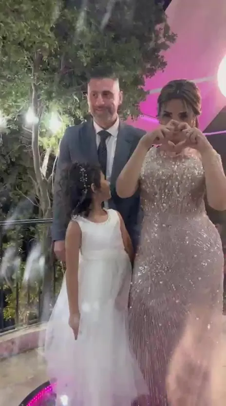 A couple and their daughter on the 360 cam platform, one of them making a heart with her hands