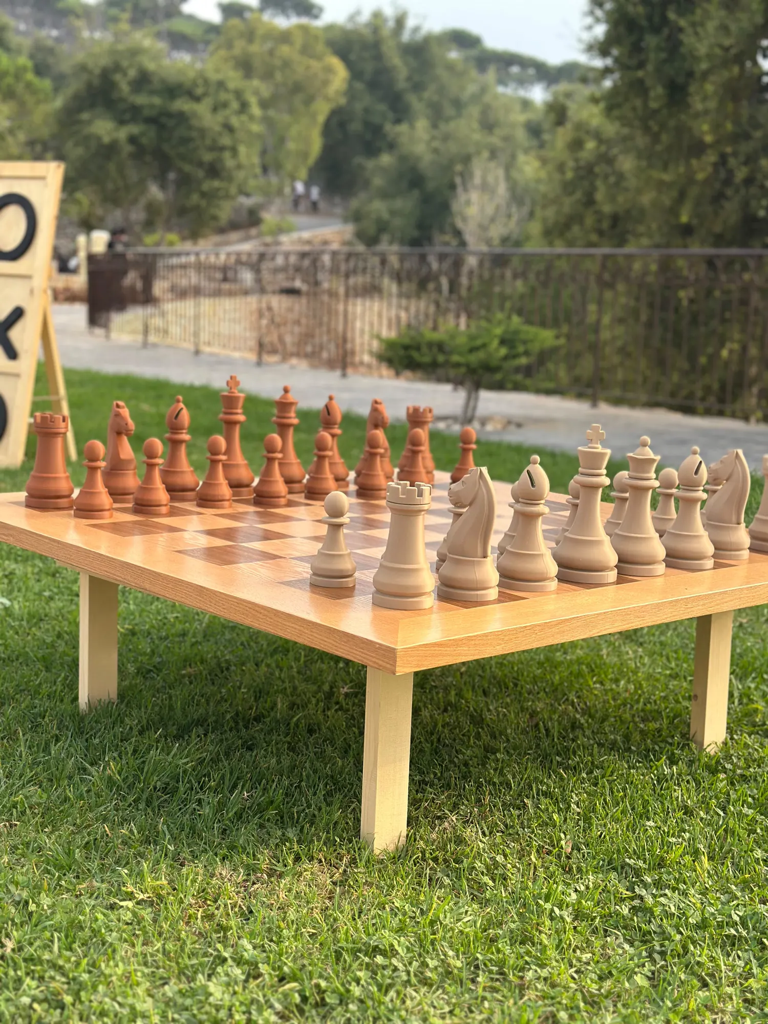 A giant chess set laid out on a lawn under trees