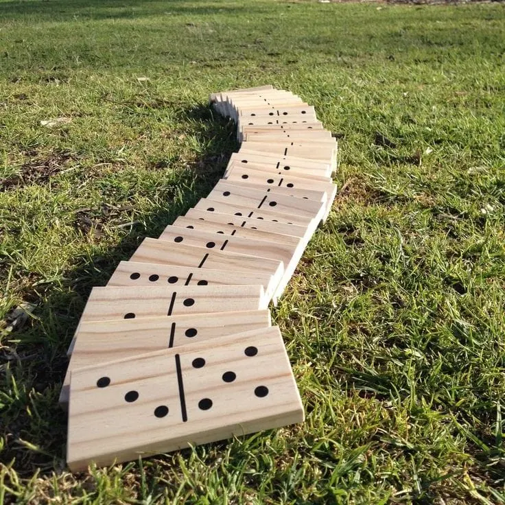 Giant wooden dominoes curving across a lawn