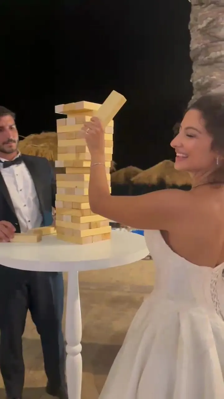 A bride laughing as she pulls a block from a giant Jenga tower