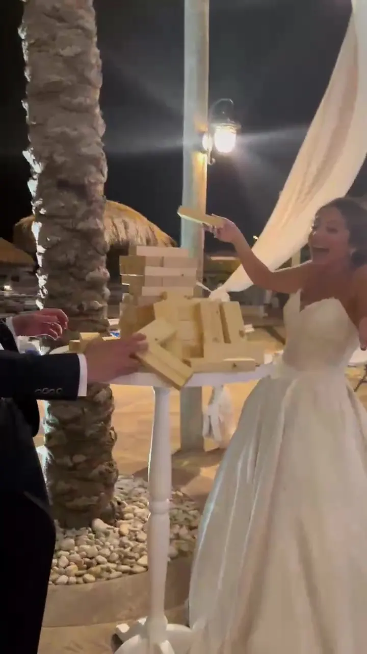A groom taking his turn at a giant Jenga tower