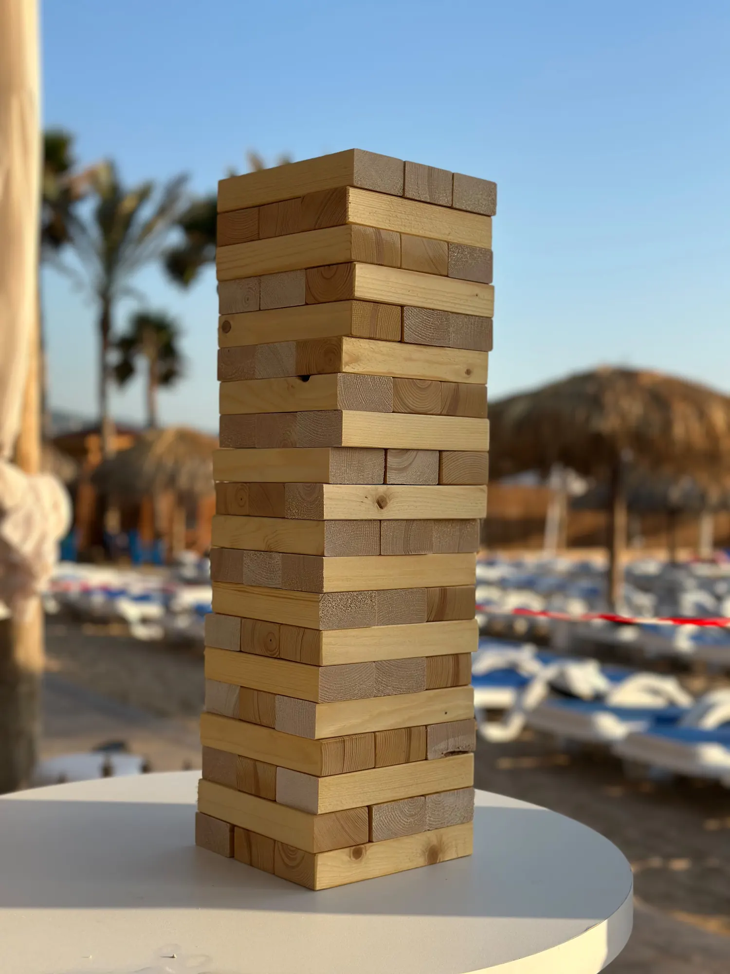 A giant Jenga tower standing on a white table by the sea