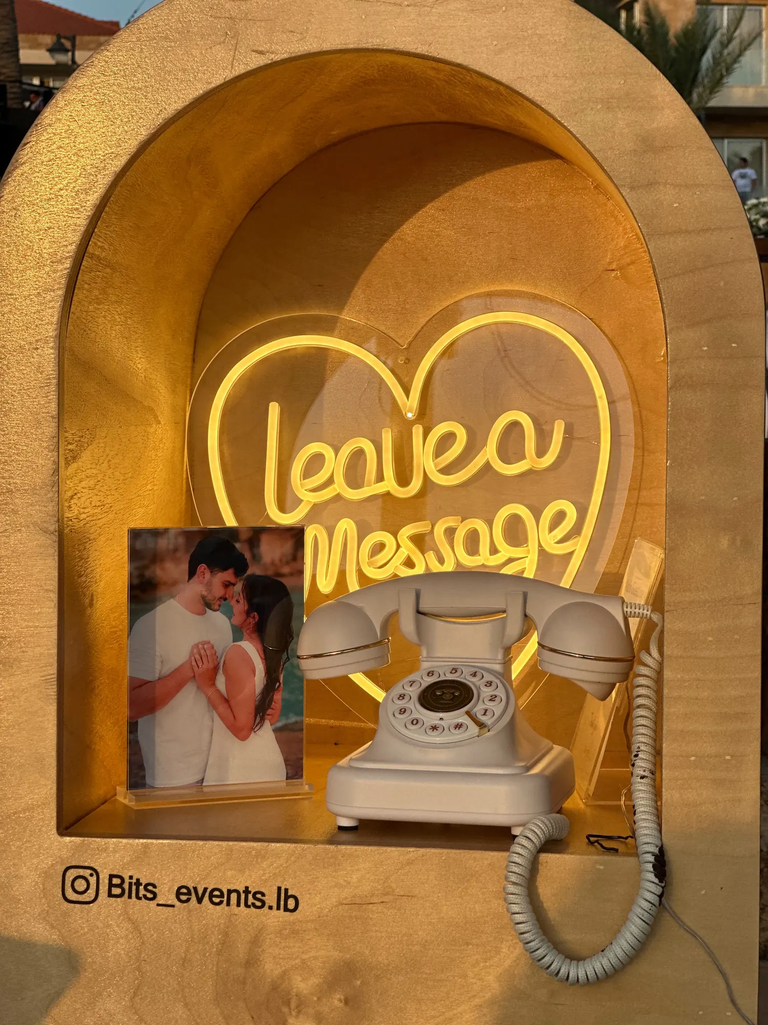 A wooden booth with a neon Leave a Message sign and a vintage telephone