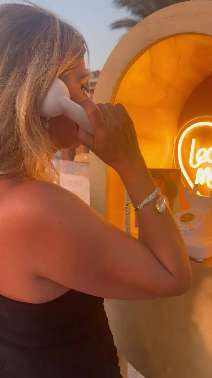 A guest speaking into the vintage handset under the neon heart
