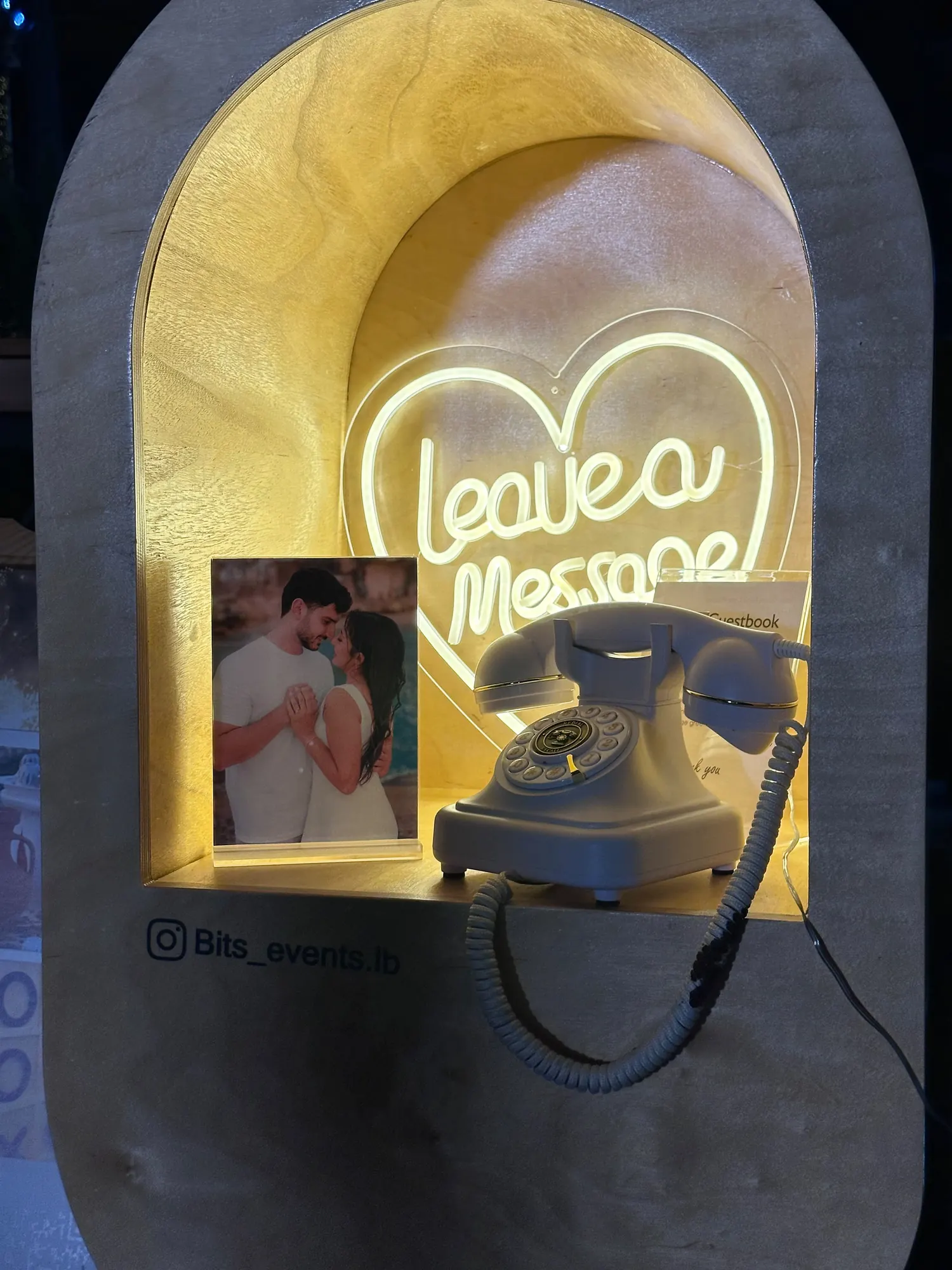 The Leave a Message neon heart glowing over a vintage telephone at night