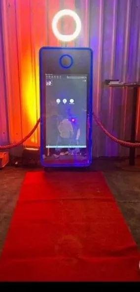 A mirror photo booth glowing at the end of a red carpet