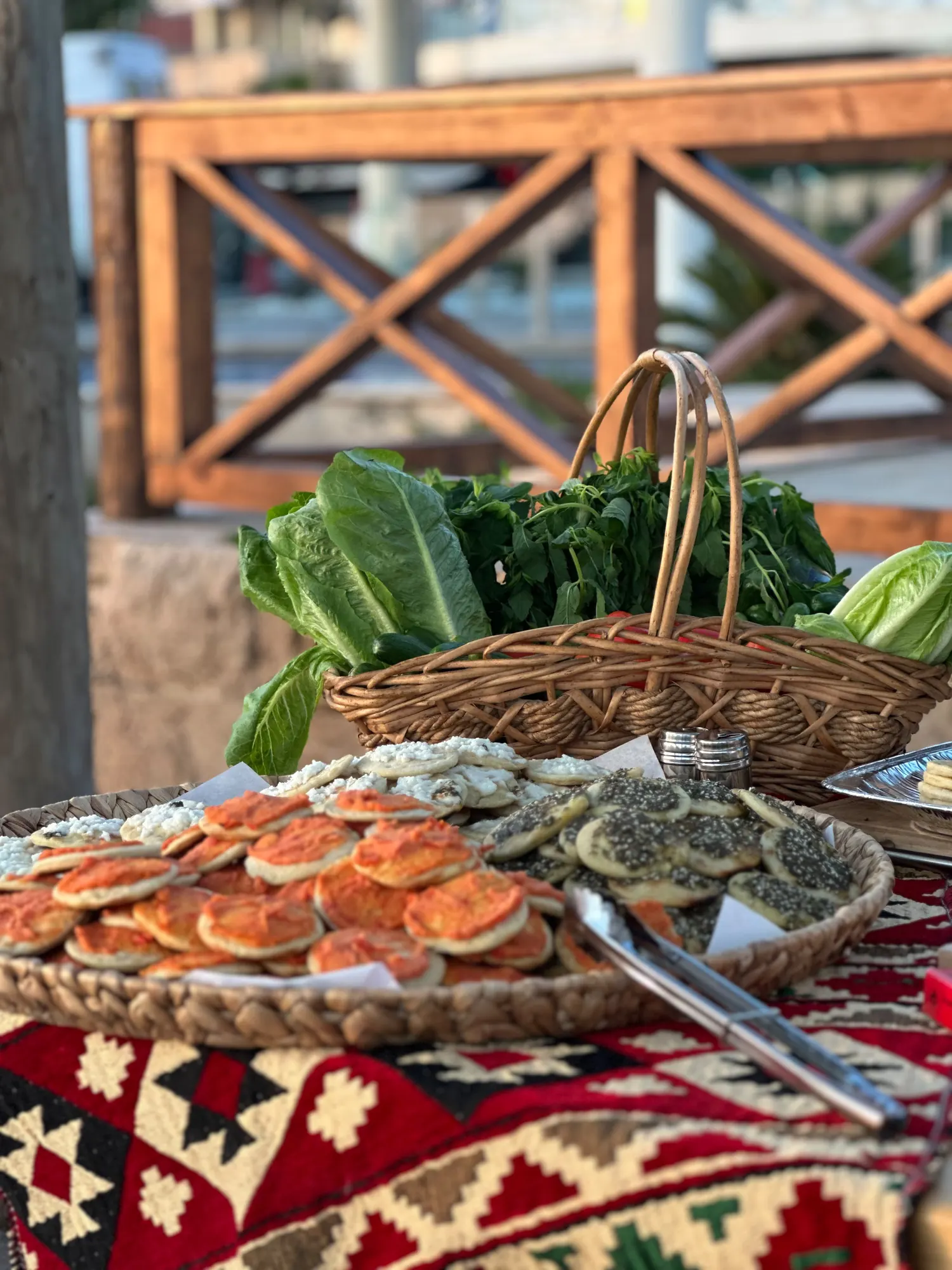 A spread of freshly baked manakish beside a basket of greens