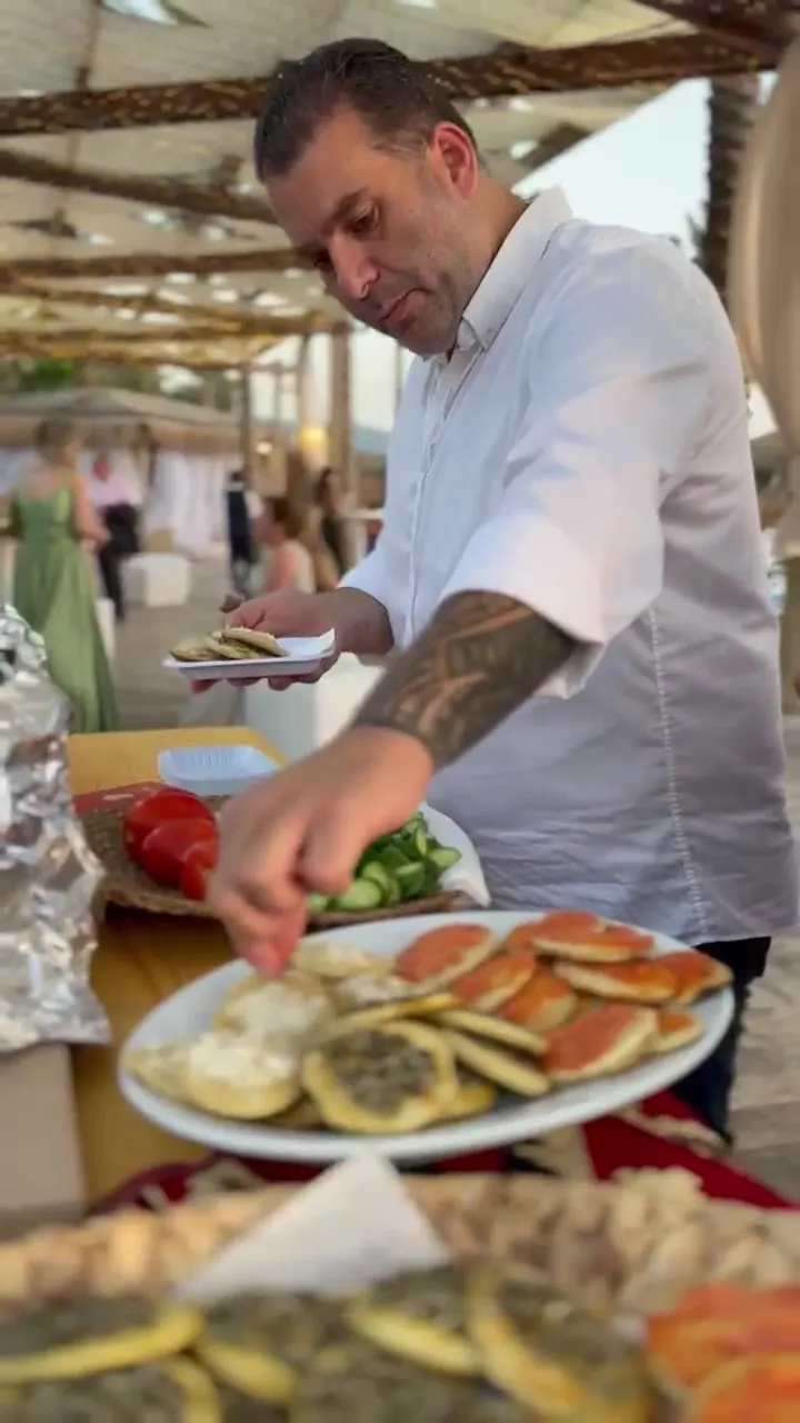 A chef plating manakish at the saj station during an event