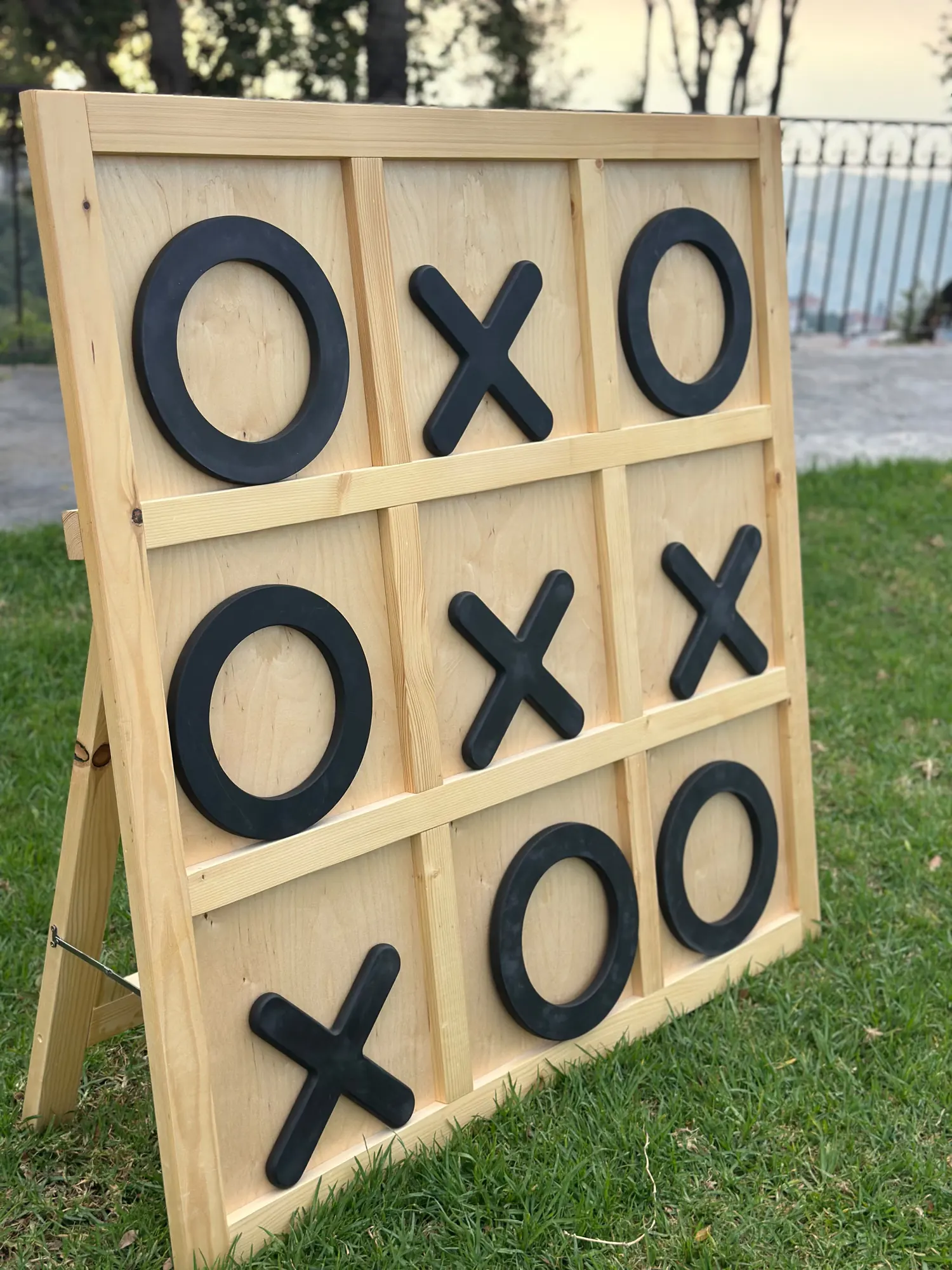 A giant XO board standing on a lawn at dusk