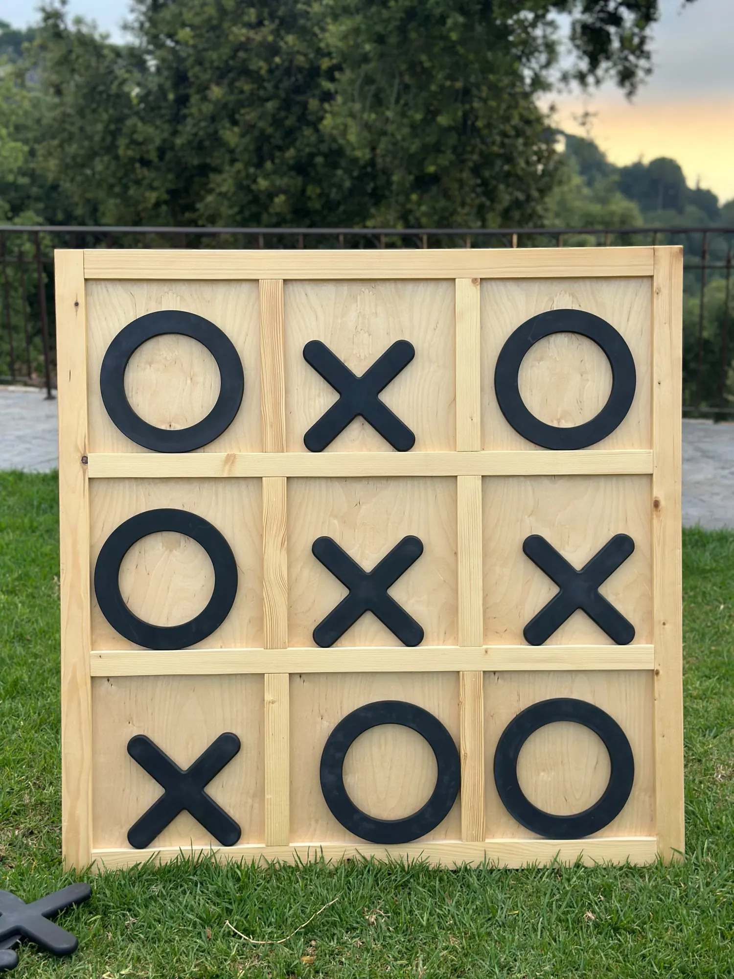 A giant XO board on a lawn with the sun setting behind it